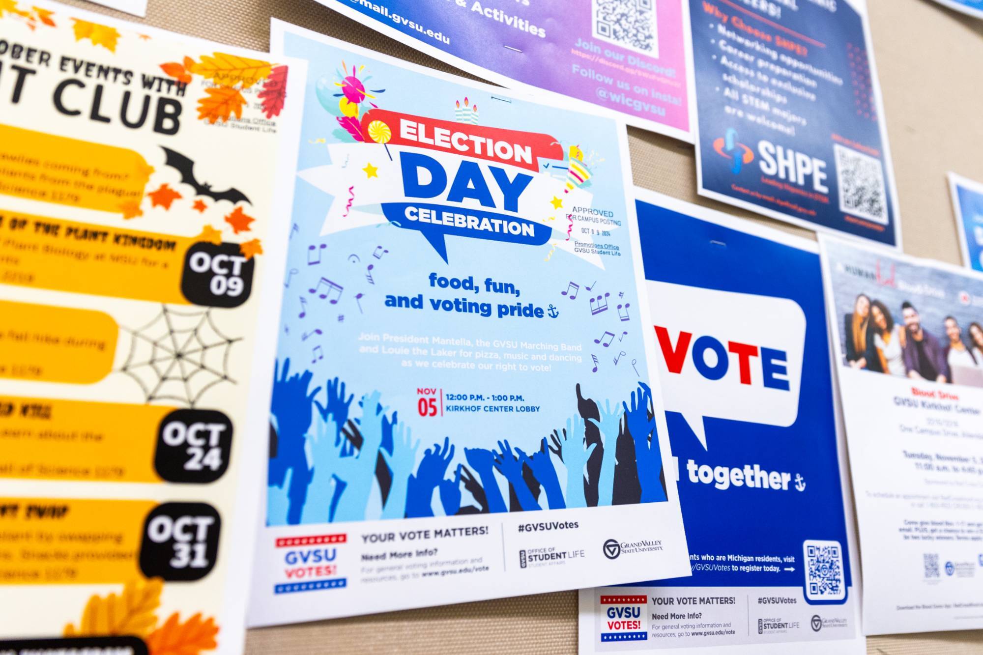 A flyer that says Election Day Celebration food, fun, and voting pride on a board of other posters